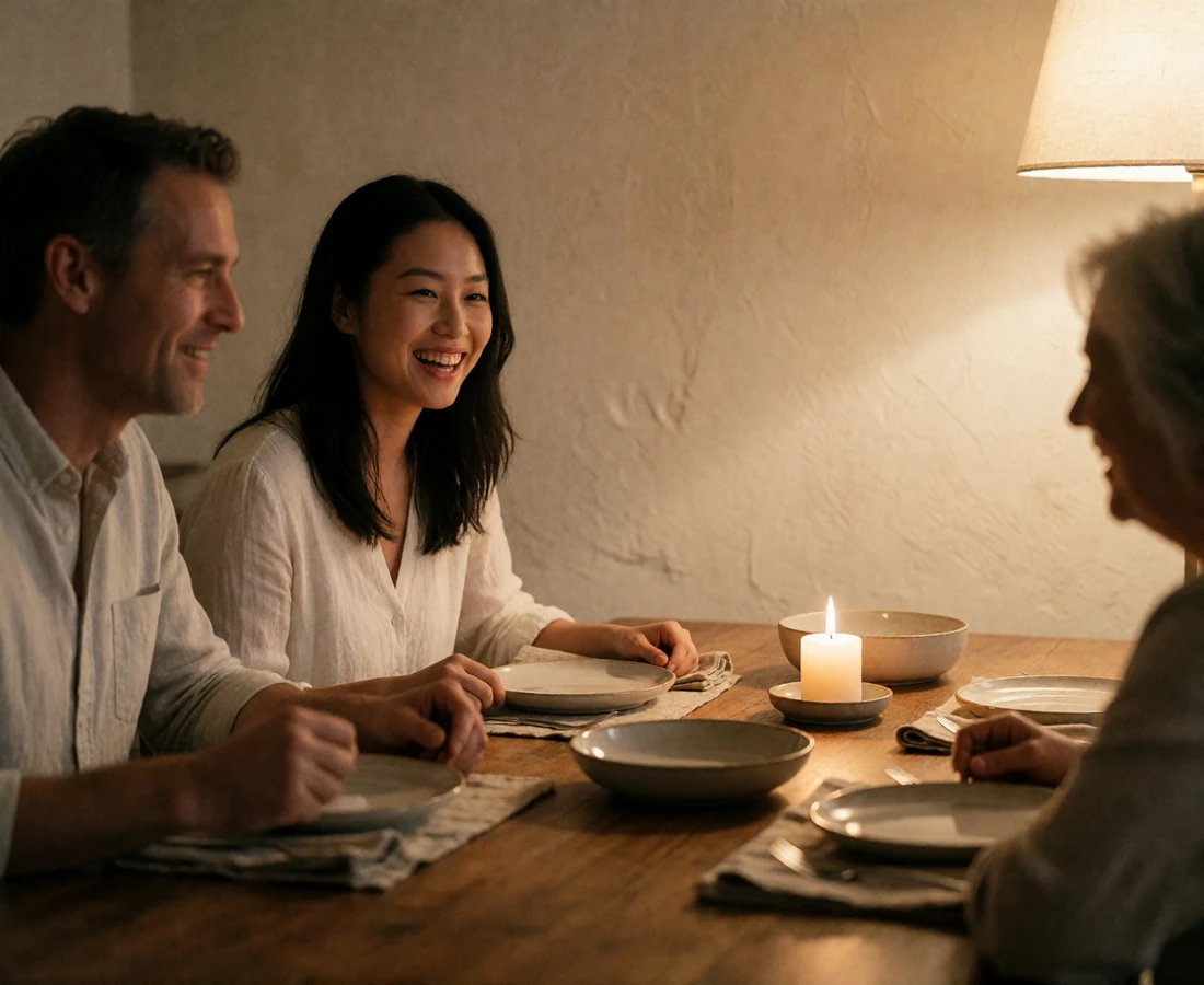 Asian woman laughing with her partner at a warm family dinner table with older relatives softly out of focus