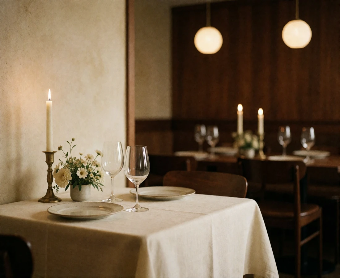 Elegant restaurant table set for two with pale linen, thin-stemmed glassware and a softly blurred dining room